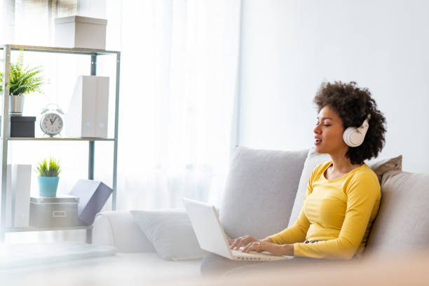 istock Smiling young woman watching a video with her laptop while siting on a sofa 1173962396