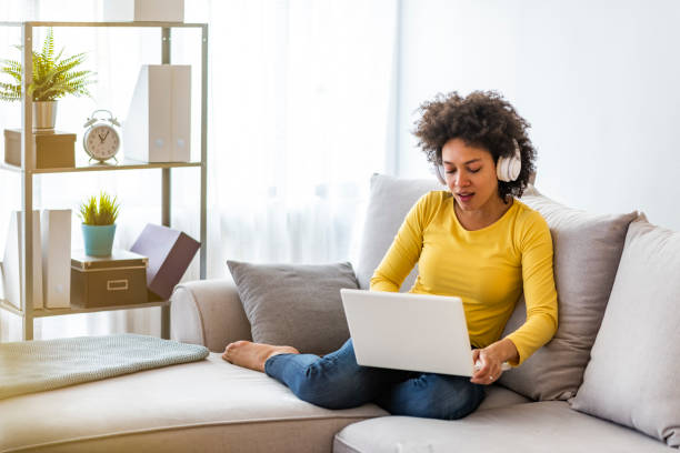istock Smiling young woman watching a video with her laptop while siting on a sofa 1173963031