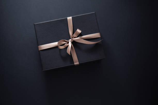 istock gift wrapped in dark black paper with luxury bow 1173963777