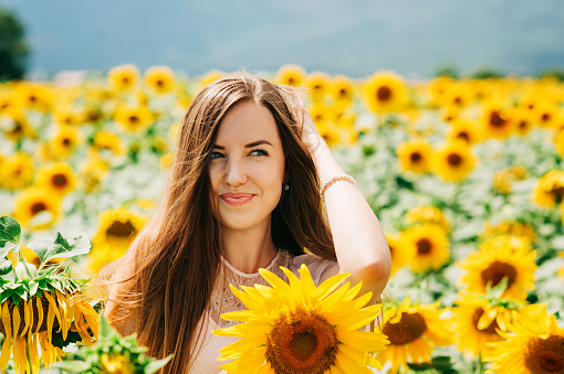 Outdoor portrait of beautiful young woman with sunflowers, health and lifestyle