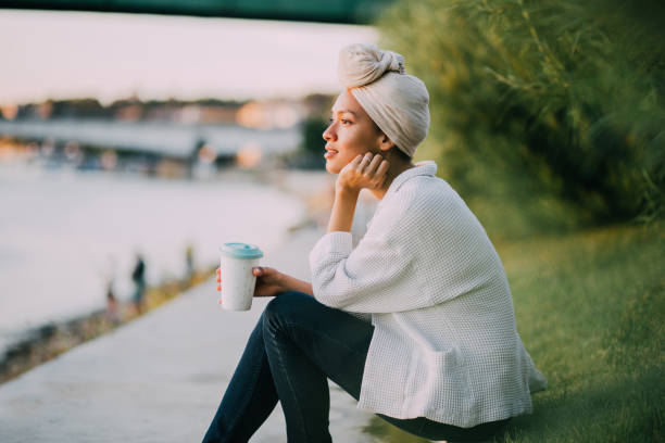 muslim girl enjoying coffee by a river - womens issues imagens e fotografias de stock