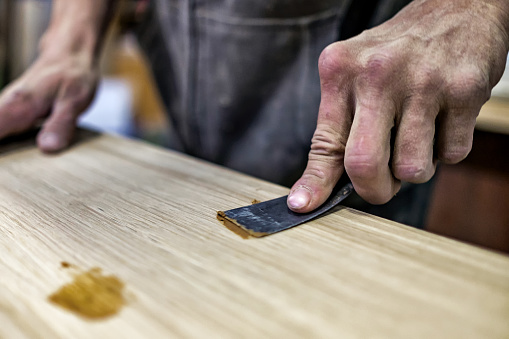 Cuchillo de putty en mano de hombre. Eliminación de agujeros de una superficie de madera. photo