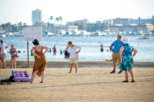 Barcelona, Spain, August 22, 2019: Group of pensioner practicing yoga and stretching by the seashore during summertime in Barcelona coast.