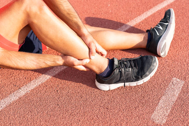 Sport injury, A man has ankle pain during outdoor exercise. knee Injuries young sport man with strong athletic legs holding ankle with his hands in pain after suffering muscle injury during a running workout on Running Track. Healthcare and sport concept. tendon stock pictures, royalty-free photos & images