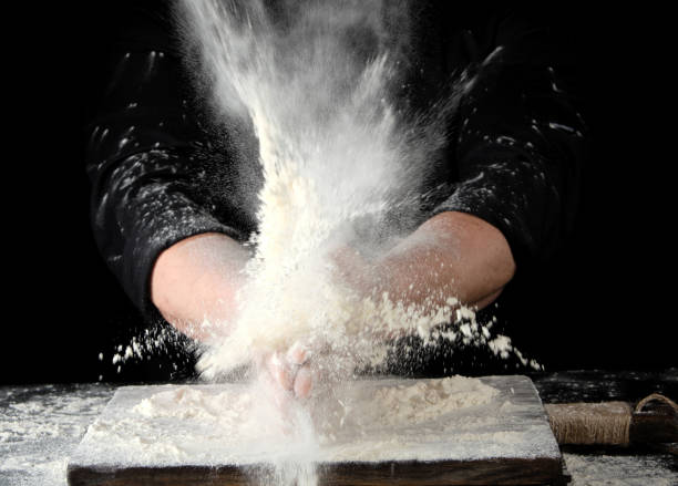 istock chef in black uniform sprinkles white wheat flour in different directions 1174003559
