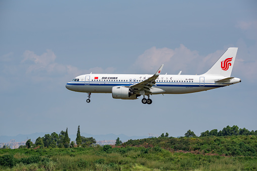 Chengdu airport, Sichuan province, China - August 28, 2019 : Air China Airbus A320 Neo commercial airplane landing in Chengdu with the city in the background
