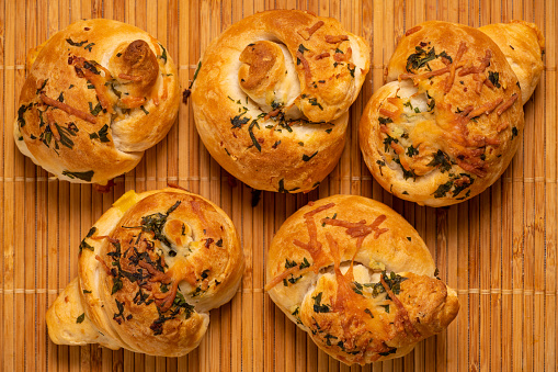 Appetizing garlic bread buns seasoned with cheese, onion, and garlic.