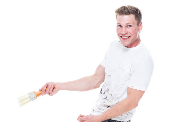 istock Young male painter with stained clothes on white background - look at camera, show to side 1174012249