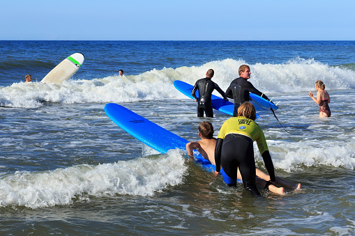 ZELENOGRADSK, RUSSIA - JULY 29, 2017: Unknown children resting and learning of surfing with professional instructors on the blue waves of the Baltic Sea at summer time.