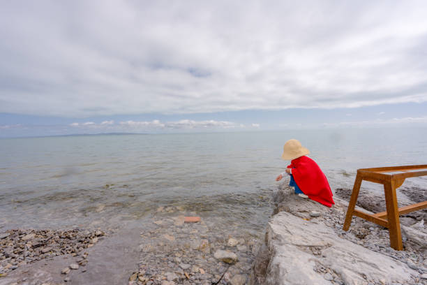 a young girl playing by the lake side, feeding the fishes