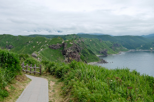 Wooden pathway on mountain, the green hills on top view,clear sky and windy along sea view,good trail at Cape Kamui Island in Shakotan,Hokkaido,Japan