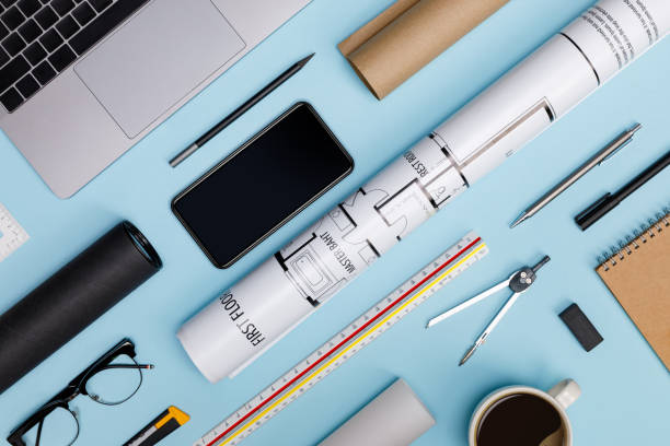 istock Creative flat lay of architects blue table with laptop computer, roll blueprints, architectural project plan, engineering tools, office supplies, isolated on blue background, Workspace for designer 1174025624