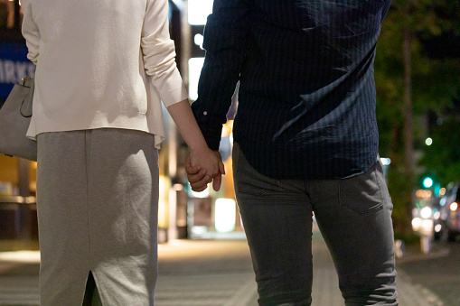 Back view of men and women holding hands in downtown at night