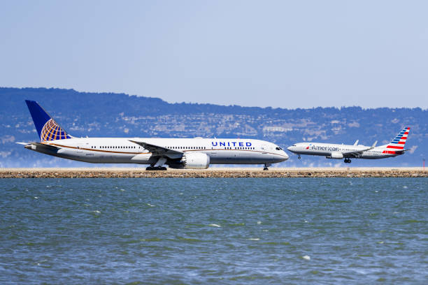 united airlines aircraft preparing to take off and american airlines aircraft landing at san francisco international airport (sfo) - san francisco international airport san francisco bay area sfo airplane imagens e fotografias de stock