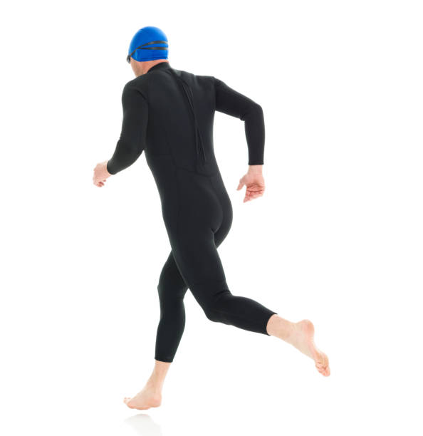 full length / one man only / rear view of 30-39 years old handsome people caucasian male / mid adult men / mid adult triathlete doing triathlon / swimming / running / exercising in front of white background - swimming male isolated swimming goggles imagens e fotografias de stock