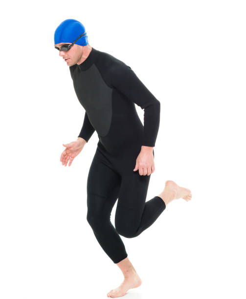 full length / one man only / side view / profile view of 30-39 years old handsome people caucasian male / mid adult men / mid adult triathlete doing triathlon / swimming / running / exercising in front of white background - swimming male isolated swimming goggles imagens e fotografias de stock