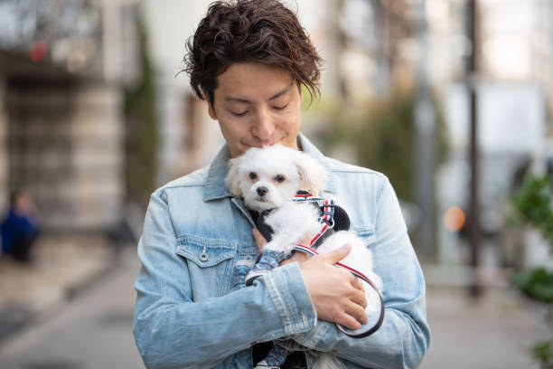 istock Man embracing puppy on street 1174042485