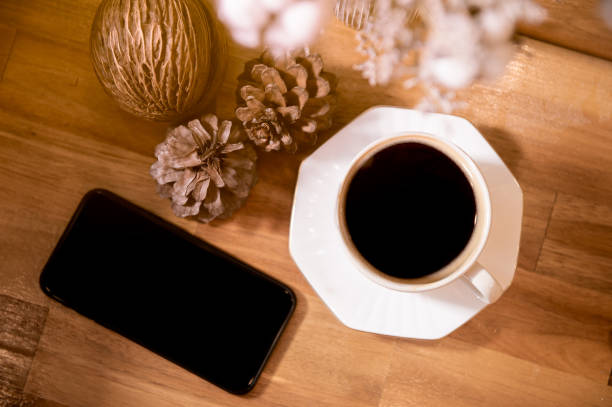 Smart phone and coffee cop on wood background.