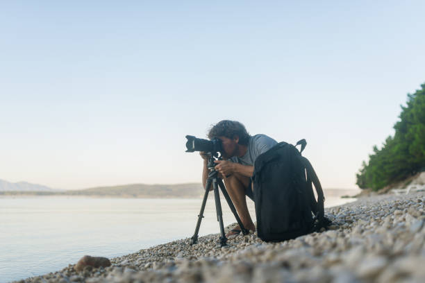 istock Male photographer taking photos on a pebble beach 1174051596