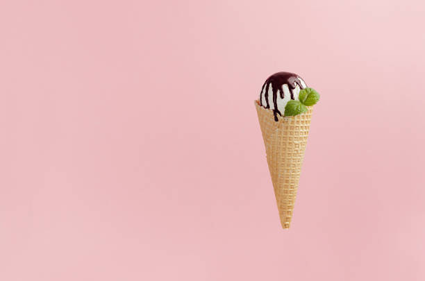 istock Classic white ice cream in crisp waffle cone with chocolate sauce, green mint leaf on pink background, copy space. 1174059573