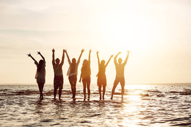 istock Group of friends having fun and greeting sunset 1174059819