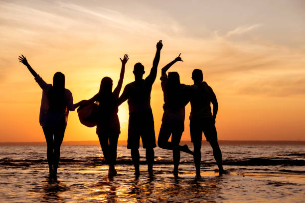 istock Happy friends silhouettes at sunset beach 1174060031