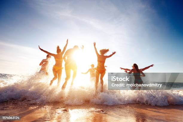 Big Group Happy Friends Runs And Having Fun At Sunset Beach Stock Photo - Download Image Now