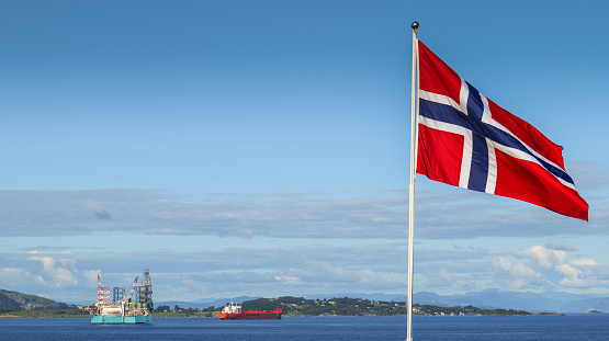 Stavanger, Norway, September 08 - An oil platform stands out against the horizon of the Stavanger Bay while a Norwegian flag flies in the sun. The oil industry is Norway's main source of wealth and in particular the Stavanger region, a nerve center for the oil companies operating in the country.