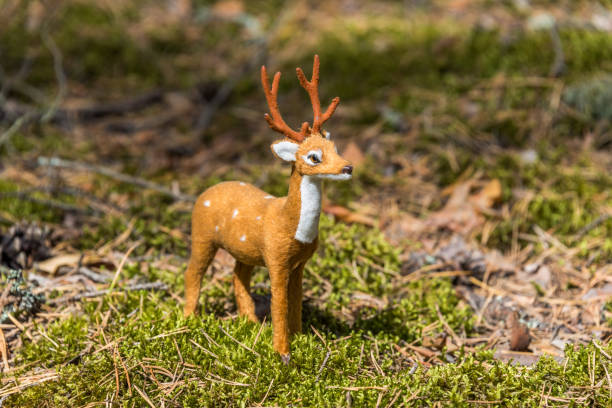 istock Little Toy Deer in a Green Forest on a Sunny Day 1174065354