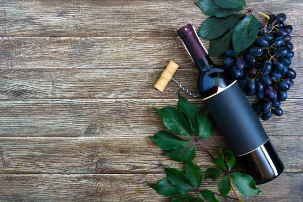istock Bottle with red wine, corkscrew, blue grapes, leaves on a wooden table. Wine background with copy space. Top view, flat lay 1174066323