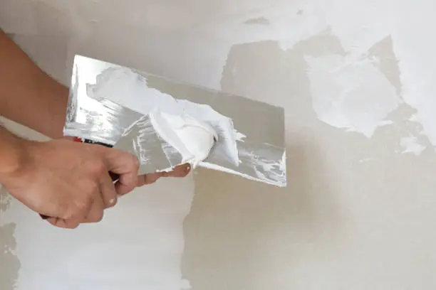 Process of plastering wall with putty-knife. Fixing wall surface and preparation for painting, home renovation concept