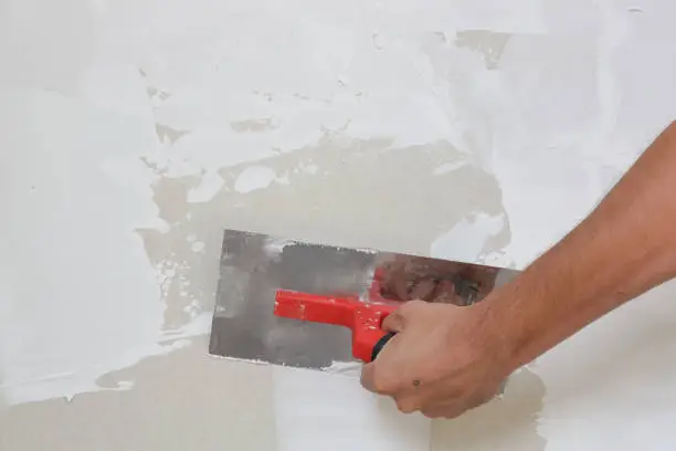 Process of plastering wall with putty-knife. Fixing wall surface and preparation for painting, home renovation concept