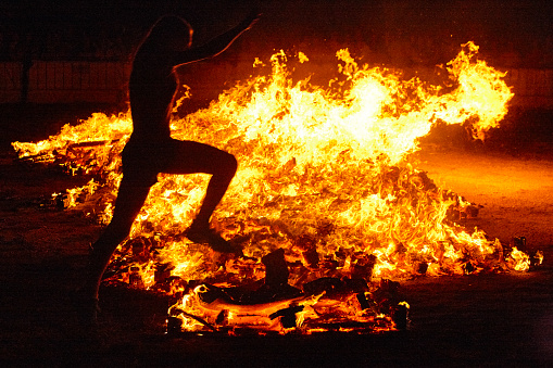 Summer solstice celebration in Spain. Woman jump. Fire flames. Horizontal