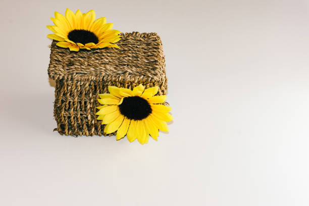 brown wicker basket decorated with yellow flowers on background