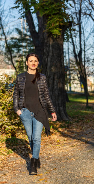 istock Young Woman Walking in an Autumn Park 1174081430