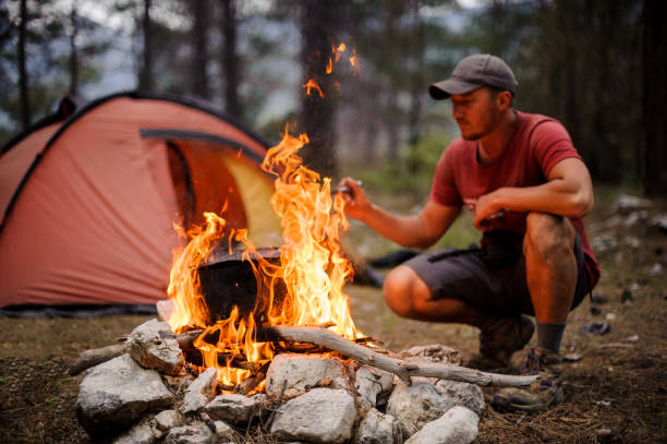istock Man in the cap sitting near the pot on the campfire 1174084749