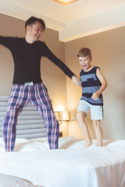 istock Happy father and son jumping on the bed. 1174091287