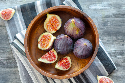 Ripe fig fruits are in the wooden bowl ,top view.