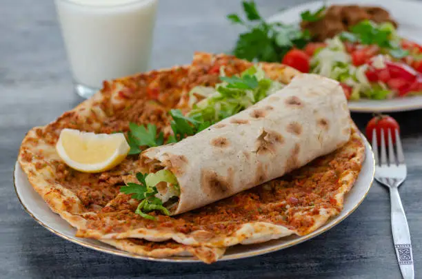 Traditional delicious Turkish food; Turkish Lahmacun ready for meal with salad and buttermilk on table.