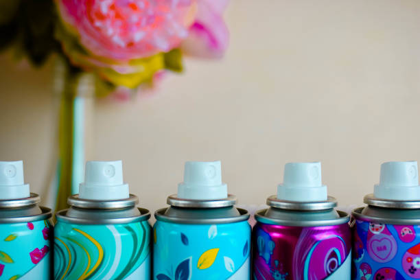 Five deodorant nozzles close up. Five colorful spray bottles with biege blurred background.