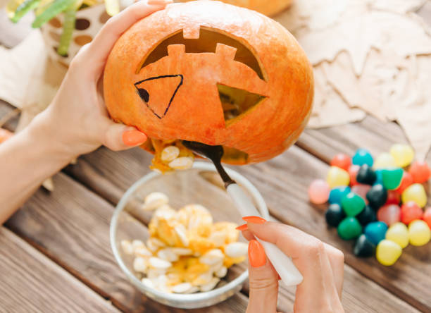 istock Female hands preparing jack-o-lantern pumpkin for Halloween holiday. 1174099949
