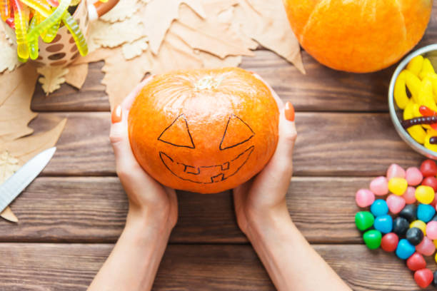istock Female hands holding pumpkin with drawing Jack-o-lantern sketch. 1174100387