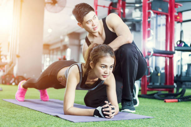 istock Sportive woman doing plank exercise training back and press muscles with trainer. Sport fitness workout strength power concept. 1174101845