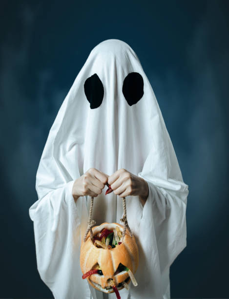 istock White ghost holding a pumpkin with candies. 1174101913