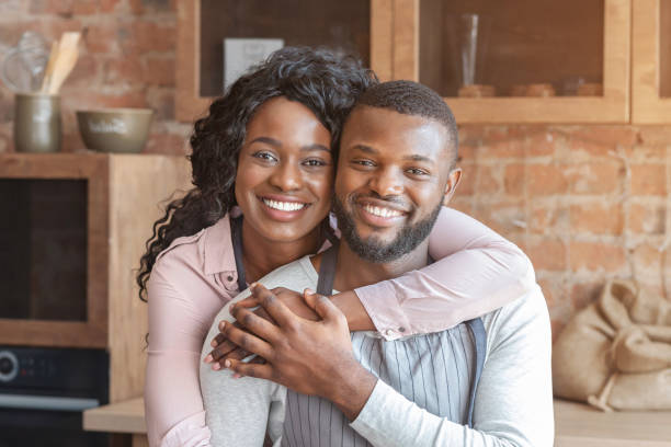 istock Beautiful african woman hugging her husband at kitchen 1174103713