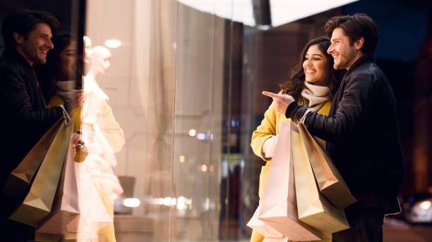 Couple looking at fashion store's window, shopping together Couple looking at fashion store's window, shopping together and walking near city center window shopping at night stock pictures, royalty-free photos & images