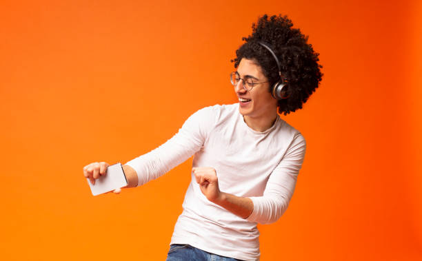 negro activo despreocupado en auriculares inalámbricos disfrutando de la música - orange white audio fotografías e imágenes de stock