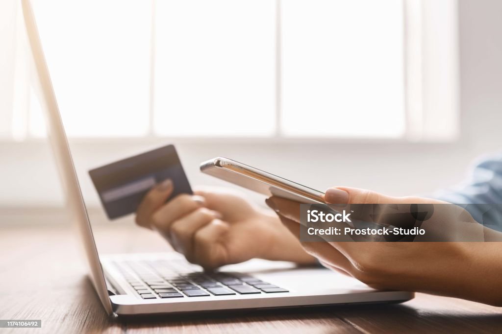 Young businesswoman booking tickets online using smartphone and credit card. Modern technologies concept. Unrecogmazable female booking tickets online preparing for business trip, using smartphone and holding credit card. Closeup Internet Stock Photo