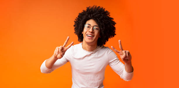 istock Cool african american guy smiling and demonstrating v-signs 1174106938
