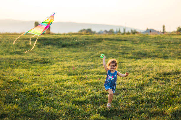 Small cute caucasian girl running with kite on meadow.